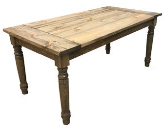 May include: A rustic wooden table with a natural wood finish and turned legs. The table has a rectangular top and is made of solid wood.