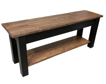 May include: A wooden bench with a black base and a lower shelf. The bench has a natural wood finish and is made of solid wood.