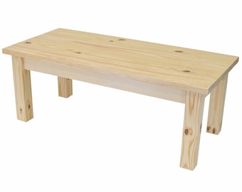 May include: A natural wood bench with a rectangular top and four legs. The bench is made of unfinished pine wood.