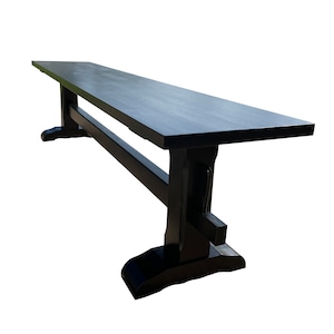 May include: A black wooden bench with a long, rectangular seat and two sturdy legs. The bench is made of solid wood and has a simple, elegant design.