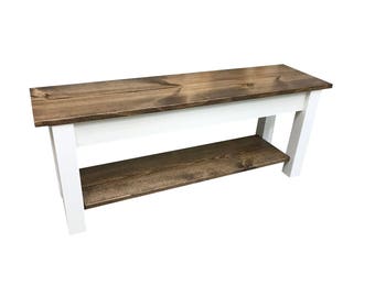 May include: A wooden bench with a white base and a lower shelf. The top of the bench is stained a dark brown color.