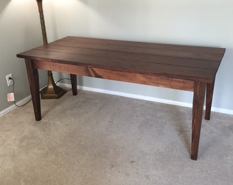 May include: A dark brown wooden table with a rectangular top and four legs. The table is sitting on a light brown carpet.