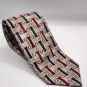 Könnte beinhalten: Eine gemusterte Krawatte mit einem sich wiederholenden Design aus dunkelroten, marineblauen und beigefarbenen Wirbeln auf hellgrauem Hintergrund. Die Krawatte ist aus einem seidigen Material gefertigt und wird auf einer weißen Oberfläche präsentiert.