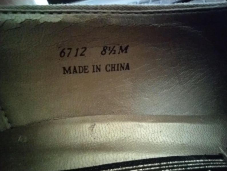May include: Close-up of the inside of a shoe. The text "6712 8 1/2 M MADE IN CHINA" is printed in black on a light beige surface. The shoe's interior is a light beige color.