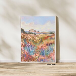 Peut inclure: Une peinture repr&eacute;sentant un paysage avec une colline au loin et un champ de fleurs color&eacute;es au premier plan. Le ciel est bleu avec des nuages blancs. La peinture est encadr&eacute;e dans un cadre blanc.