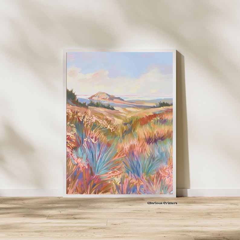 Peut inclure: Une peinture repr&eacute;sentant un paysage avec une colline au loin et un champ de fleurs color&eacute;es au premier plan. Le ciel est bleu avec des nuages blancs. La peinture est encadr&eacute;e dans un cadre blanc.