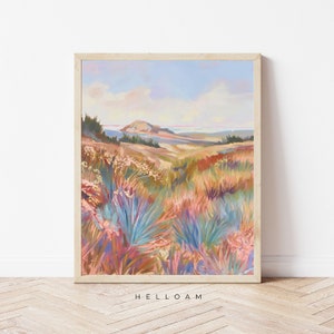 Peut inclure: Une peinture repr&eacute;sentant un paysage avec une colline au loin et un champ de fleurs sauvages color&eacute;es au premier plan. Le ciel est d'un bleu doux avec des nuages blancs. La peinture est encadr&eacute;e dans un cadre en bois clair.
