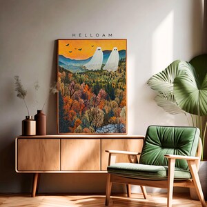 May include: A framed print of a painting depicting two white ghosts in a forest setting. The forest is filled with colorful trees and the sky is a vibrant orange. The text "HELLOAM" is at the top of the print.