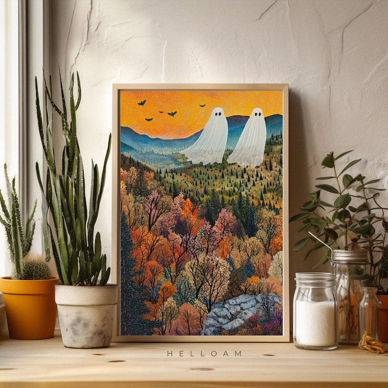 May include: A framed print of a whimsical illustration featuring two white ghosts floating over a colorful autumn forest landscape. The print has a light wood frame and the text "HELLOAM" is printed below the image.