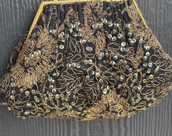 Può includere: Borsa da sera nera con ricami floreali dorati e paillettes. La borsa ha una montatura in metallo dorato e una delicata tracolla a catena. Il design della borsa è vintage ed elegante, adatta per eventi formali.