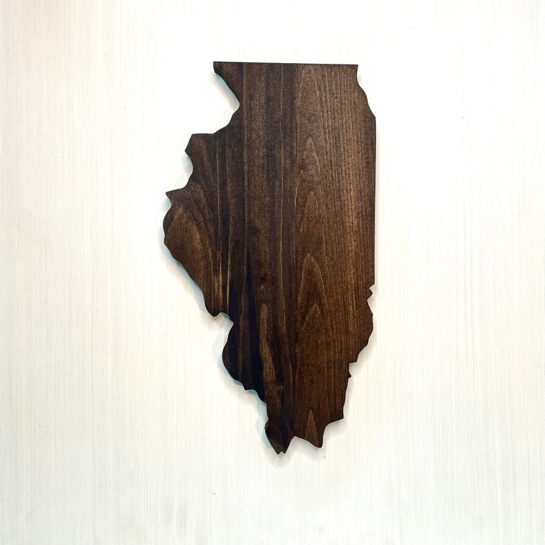 Puede incluir: Un recorte de madera con la forma del estado de Illinois. La madera tiene un tinte marr&oacute;n oscuro, resaltando la veta natural. El recorte se muestra sobre un fondo blanco.