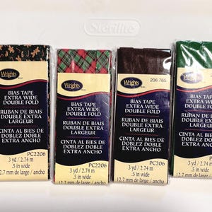 May include: Six packages of Wrights extra wide double fold bias tape in various patterns and colors, including red and white stripes, gingerbread men, red and green plaid, solid brown, solid green, and solid black, each measuring 3 yards long.