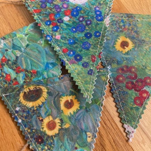 May include: A floral bunting featuring a repeating pattern of sunflowers and other flowers in shades of blue, green, red, and yellow. The pennants are strung together with natural twine.