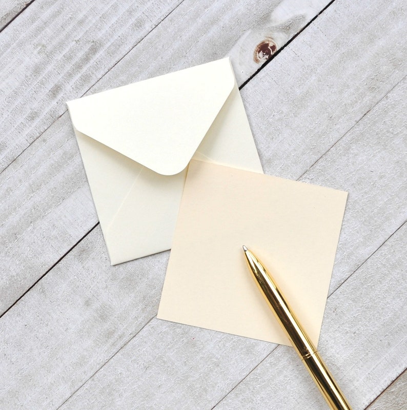 Peut inclure: Une enveloppe blanche avec un stylo dor&eacute; sur une carte de couleur cr&egrave;me. La carte est vierge et pr&ecirc;te &agrave; &ecirc;tre &eacute;crite.