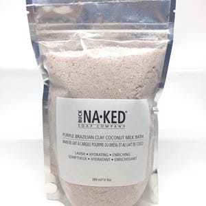 Peut inclure: Un sachet refermable argent&eacute; rempli d'un bain moussant violet. L'&eacute;tiquette indique "Buck Na-Ked Soap Company" et "Purple Brazilian Clay Coconut Milk Bath". L'&eacute;tiquette comprend &eacute;galement le texte "Lavish Hydrating Enriching" et "Somptueux Hydratant Enrichissant". Le sachet contient 389 millilitres de bain moussant.