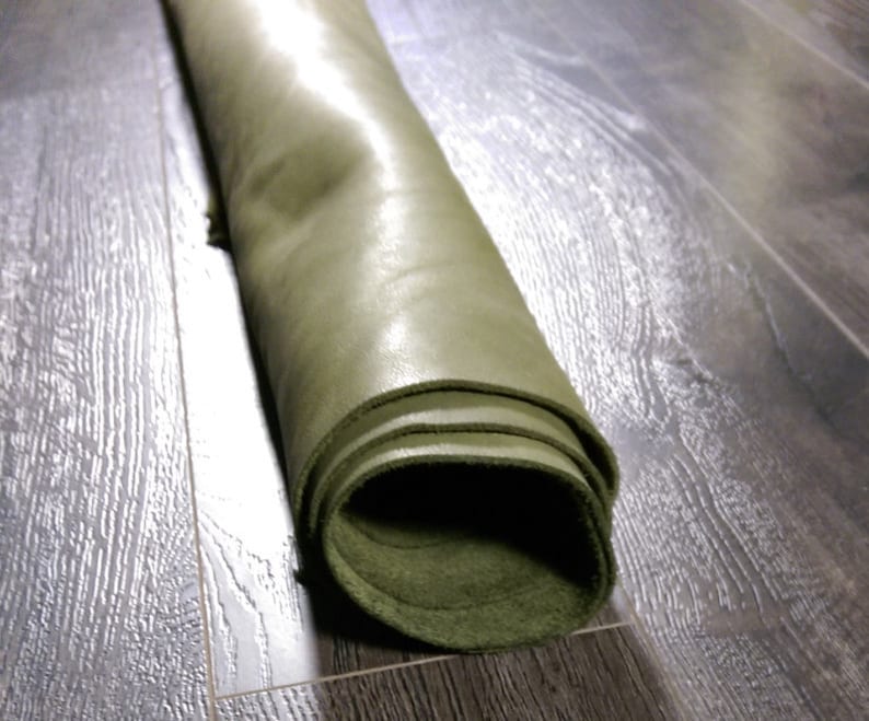 May include: A roll of dark green leather, rolled up tightly. The leather has a smooth, shiny surface.