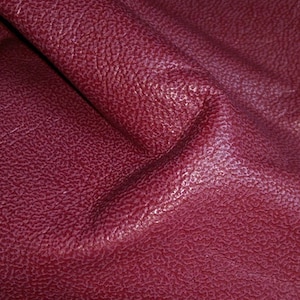 May include: Close-up of a deep burgundy leather fabric with a textured surface.