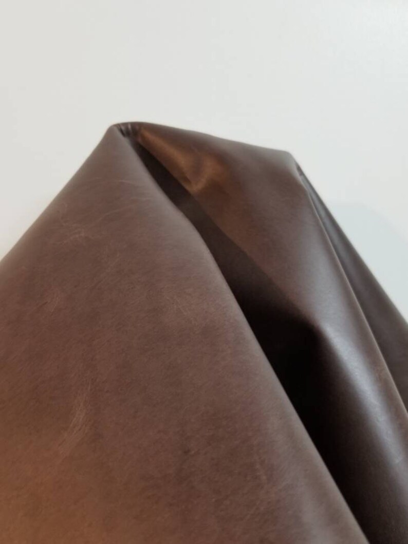 May include: A close-up of a piece of brown leather. The leather has a smooth, slightly textured surface.