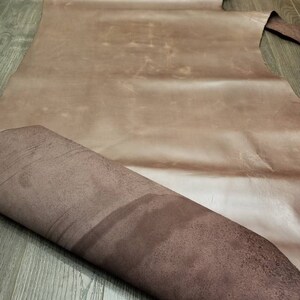 May include: A large piece of brown leather with a suede-like texture on the underside. The leather is folded in half, revealing the suede.