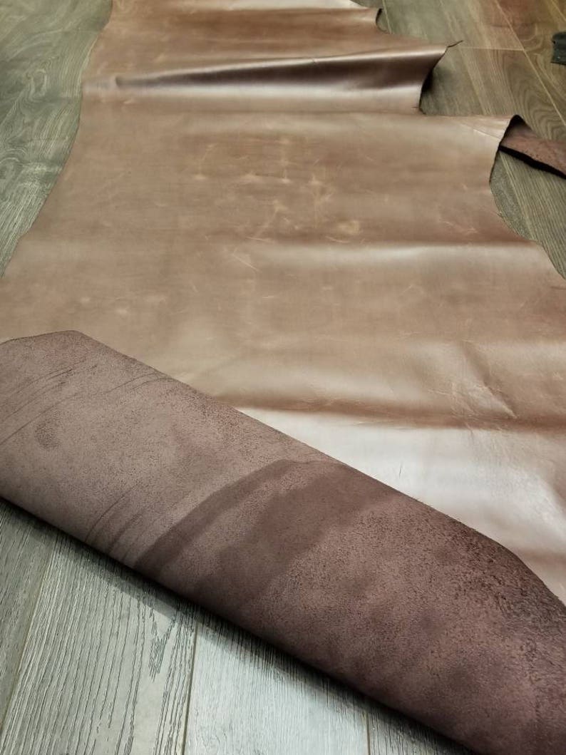 May include: A large piece of brown leather with a suede-like texture on the underside. The leather is folded in half, revealing the suede.