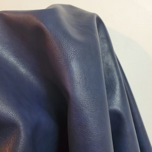 May include: A close-up of a dark blue leather fabric with a textured surface.