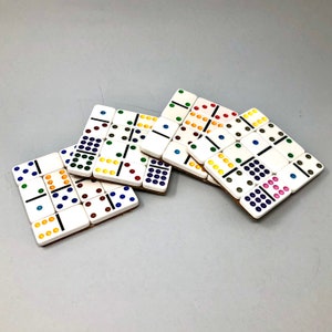 May include: A set of five white domino tiles with colorful dots. The tiles are arranged in a staggered pattern, with the dots facing up. The tiles are made of a durable material and are perfect for playing dominoes.