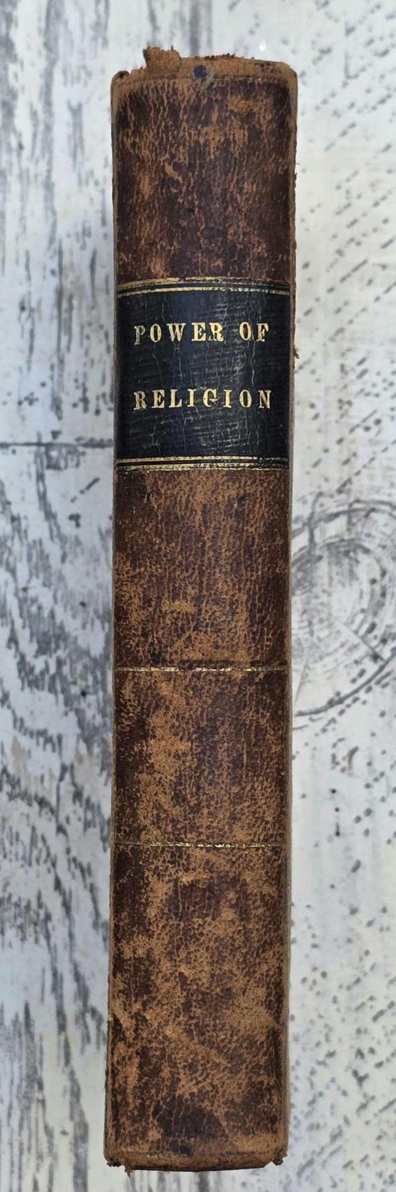 Puede incluir: Lomo de libro antiguo con el t&iacute;tulo "POWER OF RELIGION" en letras doradas sobre una etiqueta azul oscuro. La cubierta es de cuero marr&oacute;n con un aspecto envejecido y texturizado.