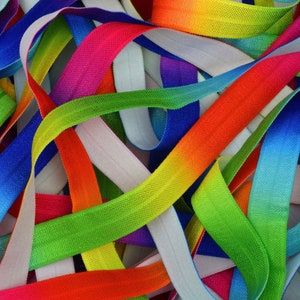 May include: A close-up of a pile of colorful elastic bands with a rainbow ombre effect. The bands are made of a soft, stretchy material and are perfect for crafts, hair ties, or other projects.
