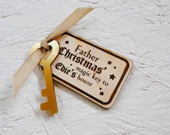 May include: A wooden key tag with the text "Father Christmas' magic key to Edie's house" and a gold-colored key attached to it.