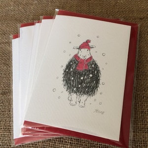 May include: A pack of five blank greeting cards with red envelopes. The card features a black and white illustration of a sheep wearing a red hat and scarf in a snowy scene. The card is signed "AF 2018".