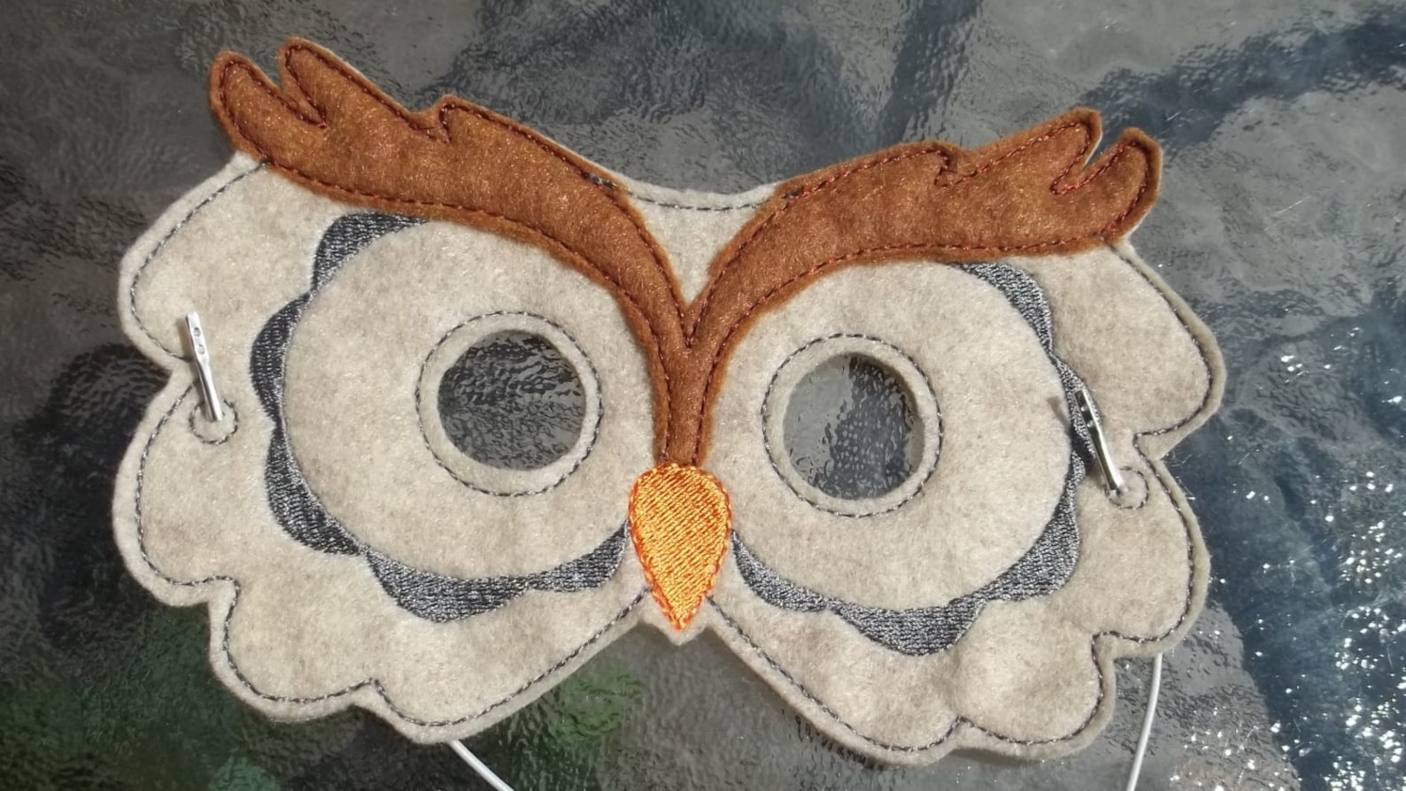 Brown and cream felt owl mask with broad eyebrows and orange beak.