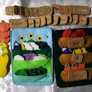 May include: A felt educational toy set featuring two rectangular boards with pockets, assorted vegetable shapes, and small rectangular labels with numbers, colors, and words like squash, red, 4, carrot, and white embroidered in various thread colors.