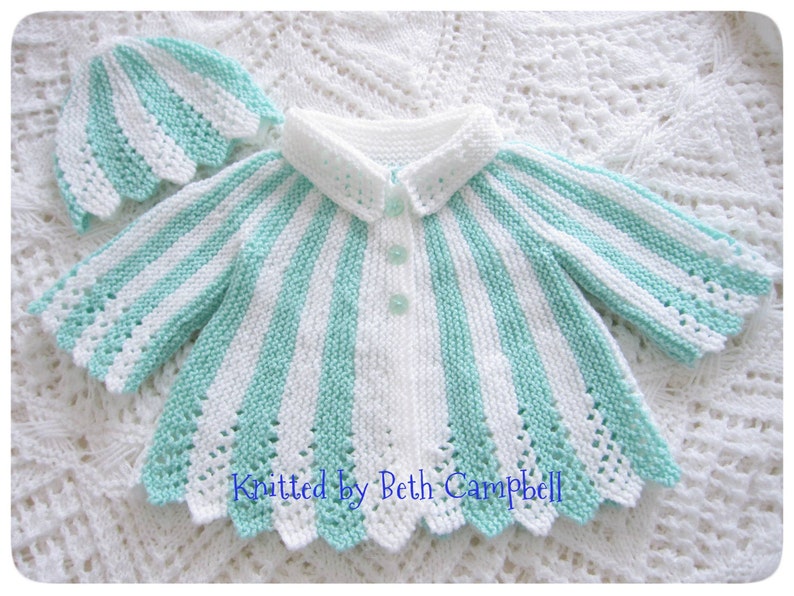 May include: A white and mint green striped knitted baby cardigan with a scalloped edge and a matching hat. The cardigan has a button closure and a white collar.