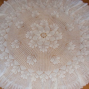 May include: White crocheted tablecloth with a delicate floral design in the center.