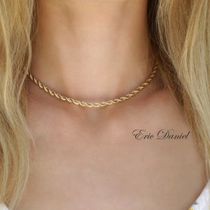 May include: A gold rope chain necklace on a model's neck. The chain is a simple, delicate design.