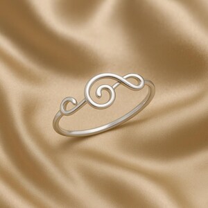 May include: A silver ring with a treble clef design. The ring is simple and elegant, making it a great choice for music lovers.
