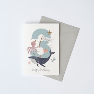 May include: A blue and white birthday card featuring a whale, octopus and crab. The number three is in the background with the word "three" written on a banner. The card reads "Happy Birthday".