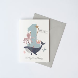 May include: A blue and white birthday card featuring a whale, octopus and crab. The number one is on the card with the word "one" written next to it. The text "Happy 1st Birthday" is at the bottom of the card.