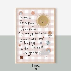 May include: A pink and white gingham print with a sun, flowers, a ladybug, a butterfly, and a rainbow. The text reads "you are my Sunshine, My only Sunshine. you make me happy when skies are grey." The text is in a handwritten style. The bottom of the print reads "little M".