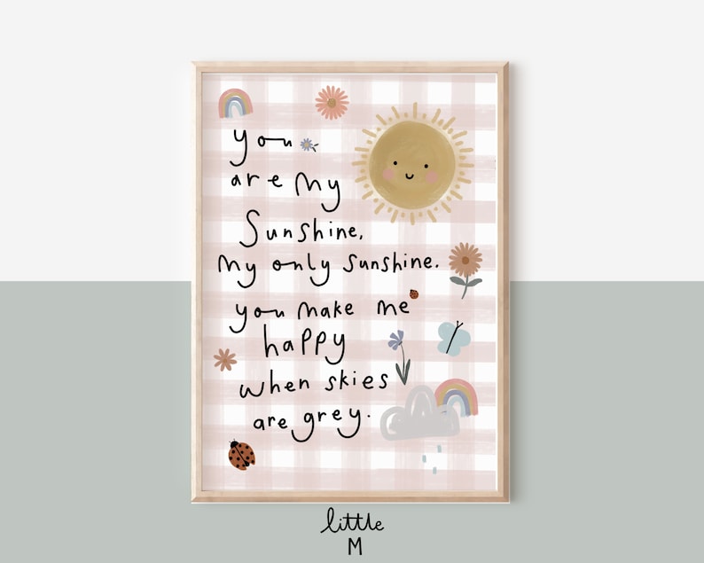 May include: A pink and white gingham print with a sun, flowers, a ladybug, a butterfly, and a rainbow. The text reads "you are my Sunshine, My only Sunshine. you make me happy when skies are grey." The text is in a handwritten style. The bottom of the print reads "little M".