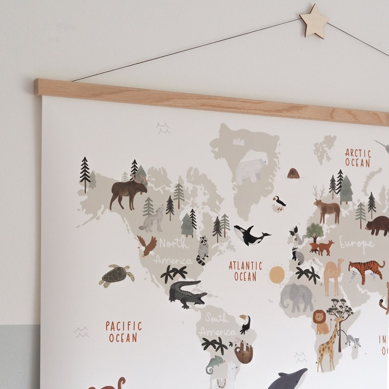May include: A colorful world map with animals from different continents. The map is printed on white paper and framed with a light brown wooden frame. The map includes the names of the continents and oceans.