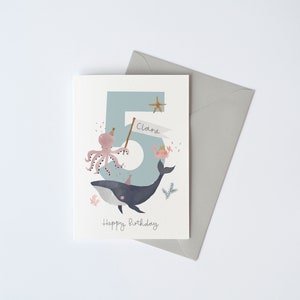 May include: A blue and white birthday card featuring a whale, octopus, and the number 5. The card reads "Happy Birthday" and "Clara" on a banner.