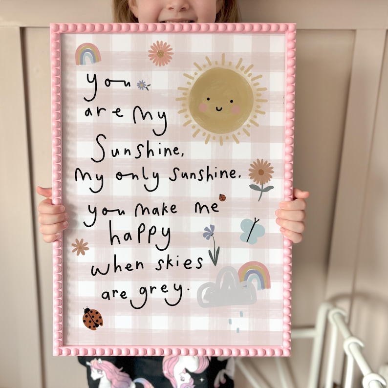 May include: A pink framed print with a gingham background and a handwritten message that reads "you are my Sunshine, My only Sunshine. you make me happy when skies are grey."