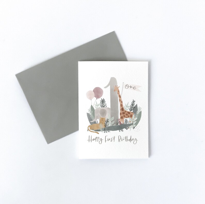 May include: A white card with a watercolor illustration of a giraffe, elephant, and lion surrounding the number one. The card says "one" and "Happy First Birthday".