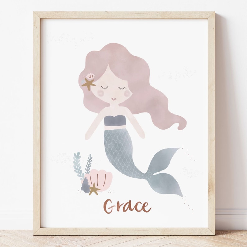 May include: A framed print featuring a watercolour illustration of a mermaid with pink hair, a blue tail, and a seashell. The mermaid is surrounded by sea-themed elements, including a starfish and seaweed. The name "Grace" is written in a copper-coloured font at the bottom of the print.