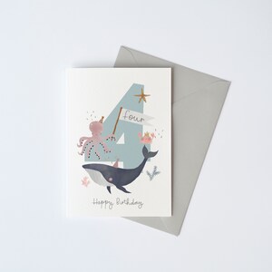 May include: A light blue card with a large number four on it. The number is decorated with a whale, an octopus, and a crab. The text "four" and "Happy Birthday" are written on the card.
