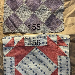 May include: Two antique quilt squares. The top square features a diamond pattern in lavender and gray. The bottom square has a red and white design with blue floral accents. Both squares have the numbers 155 and 156 printed on them.