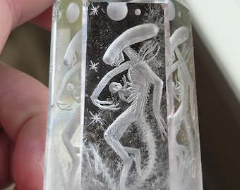 plot twist alien with baby bursting from its chest reverse intaglio carved onto a polished quartz crystal tower