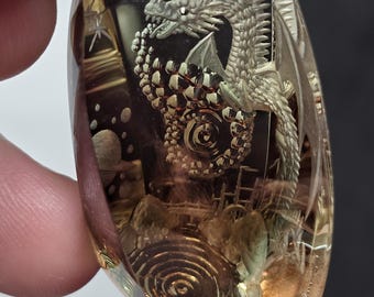 huge 100 carat dark red and green Oregon sunstone with a surrealistic dragon kingdom reverse intaglio carving