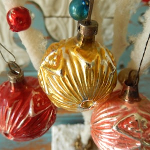 May include: Three vintage glass ornaments featuring a reflective metallic finish. One ornament is bright red, one is gold, and one is a soft coral pink. Each sphere has a textured, ribbed surface pattern and a silver-toned metal cap for hanging.
